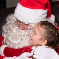 A little girl hugging Santa.